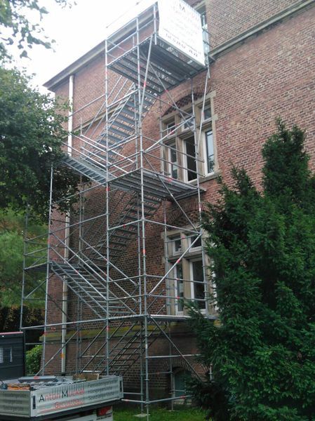 Gerüst vor der Klinkerfassade eines Altbaus mit Firmenschild