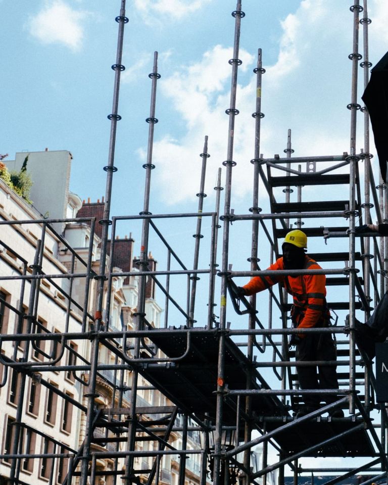Zwei Gerüstbauer arbeiten auf einem Treppenaufgang in einem Gerüst