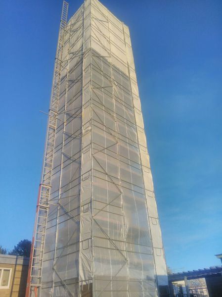 Hohes, mit Folie eingehaustes Gerüst steht frei vor blauem Himmel